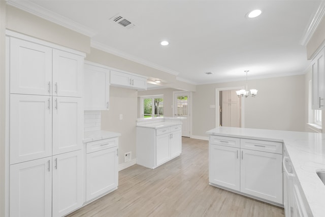 kitchen with white cabinets, pendant lighting, crown molding, and light hardwood / wood-style flooring