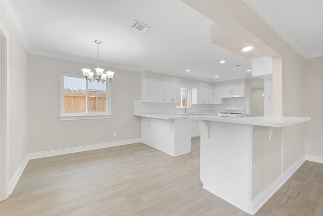 kitchen featuring kitchen peninsula, a kitchen breakfast bar, tasteful backsplash, white range, and white cabinetry