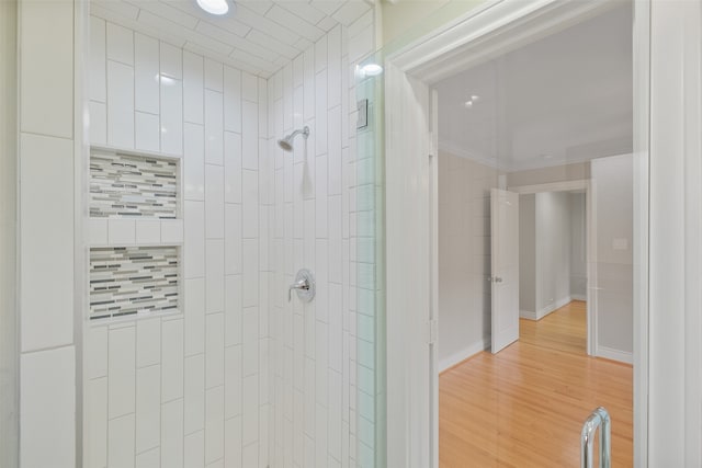 bathroom featuring decorative backsplash, hardwood / wood-style floors, and tiled shower