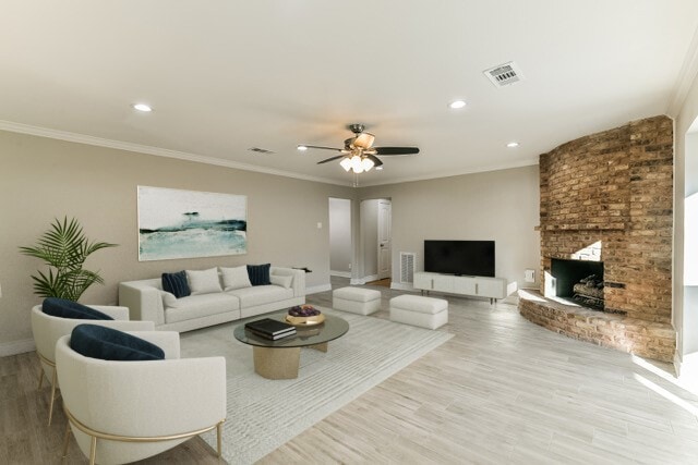 living room featuring a fireplace, light hardwood / wood-style flooring, ceiling fan, and crown molding