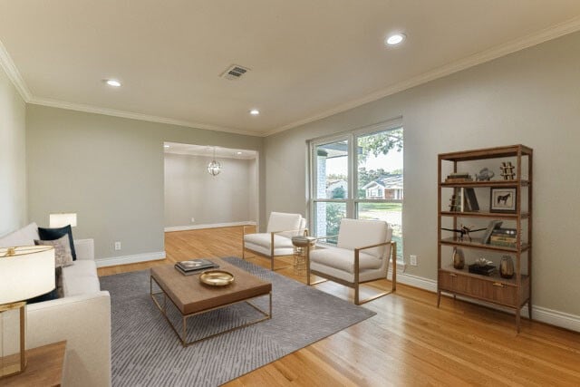 living room featuring hardwood / wood-style flooring, ornamental molding, and a chandelier