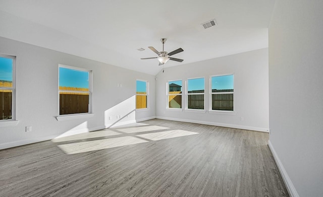 unfurnished living room with light wood finished floors, baseboards, visible vents, ceiling fan, and vaulted ceiling