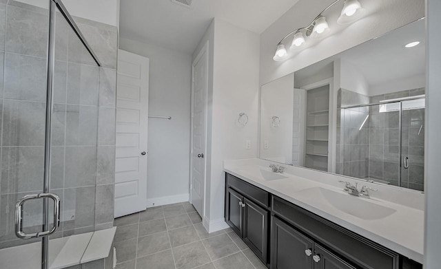 bathroom featuring a tile shower, double vanity, tile patterned flooring, and a sink