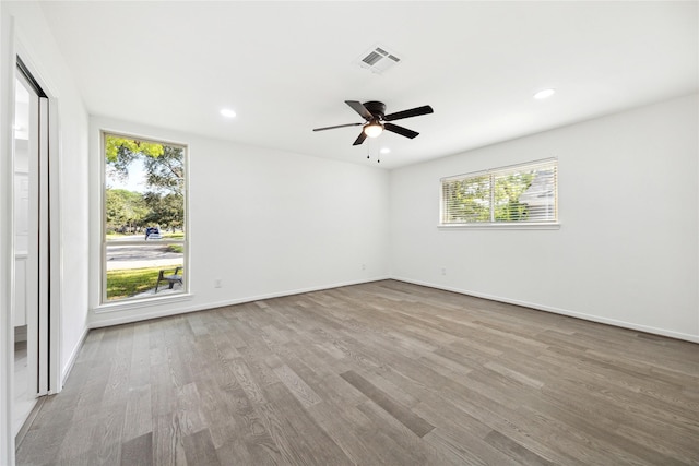 empty room featuring a wealth of natural light, ceiling fan, and light hardwood / wood-style floors