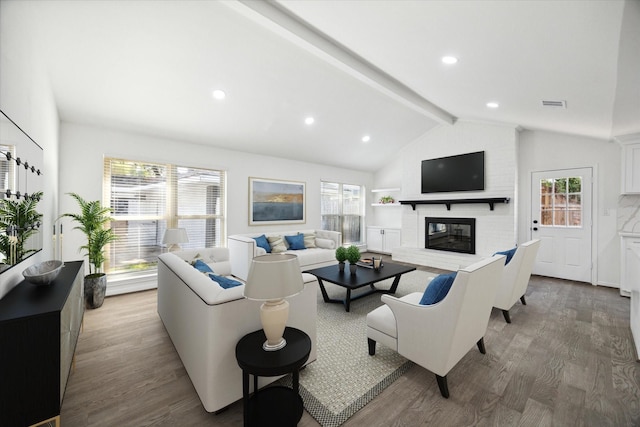 living room with hardwood / wood-style floors, lofted ceiling with beams, and a brick fireplace