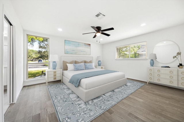 bedroom with multiple windows, hardwood / wood-style flooring, and ceiling fan