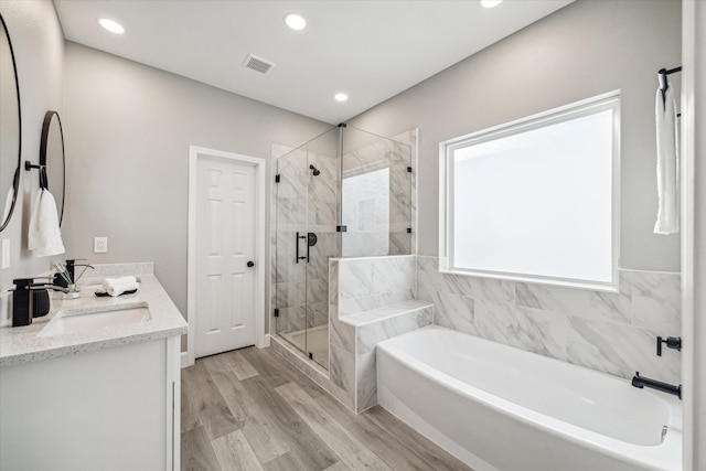 bathroom with shower with separate bathtub, hardwood / wood-style flooring, and vanity