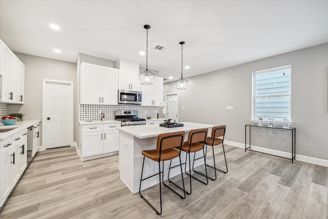 kitchen with white cabinets, stainless steel appliances, and a center island with sink