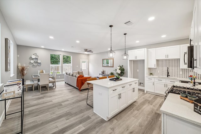 kitchen featuring a kitchen island, hanging light fixtures, light hardwood / wood-style floors, and white cabinets