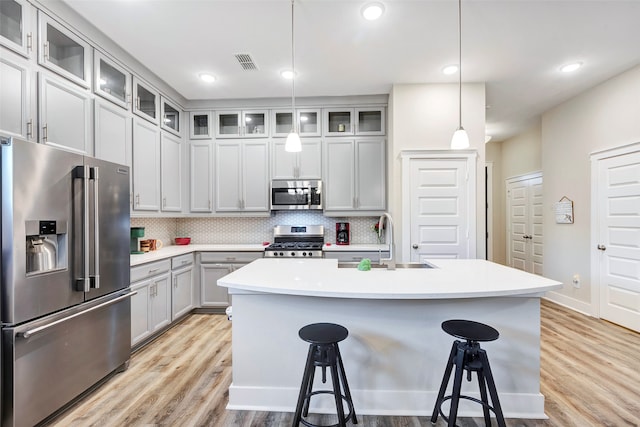 kitchen featuring a center island with sink, sink, appliances with stainless steel finishes, and a breakfast bar area