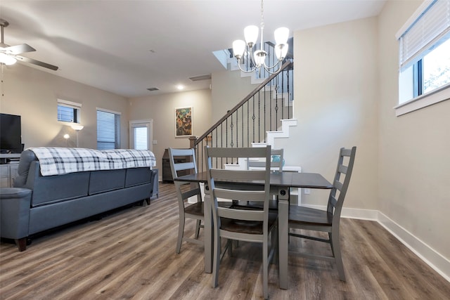 dining area with ceiling fan with notable chandelier and dark hardwood / wood-style flooring