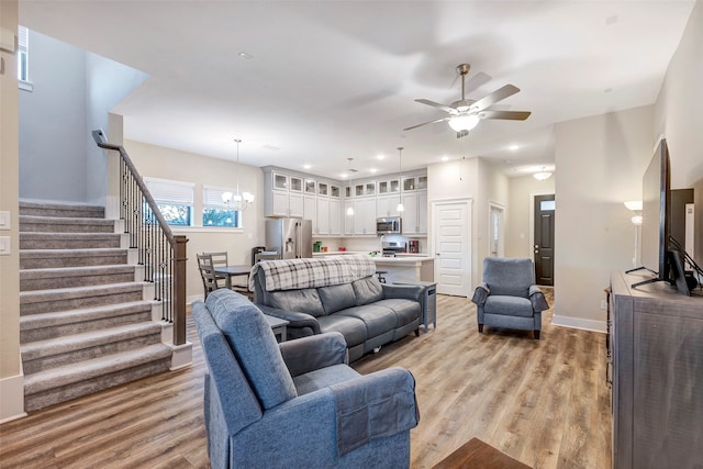 living room featuring light hardwood / wood-style flooring and ceiling fan with notable chandelier