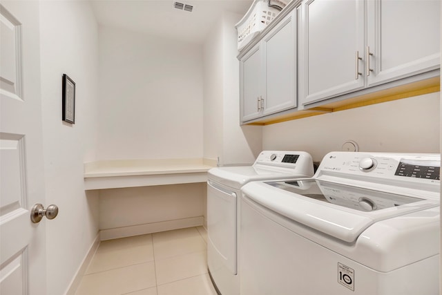 washroom with washer and dryer, light tile patterned flooring, and cabinets