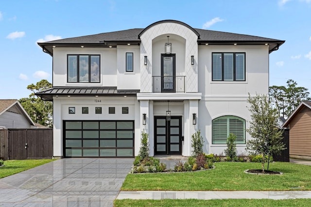 view of front of house with decorative driveway, a front yard, a standing seam roof, a balcony, and a garage