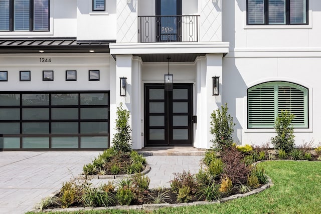 view of exterior entry with a garage and a balcony