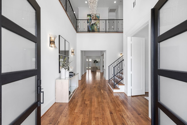 entryway with stairway, visible vents, wood finished floors, and an inviting chandelier