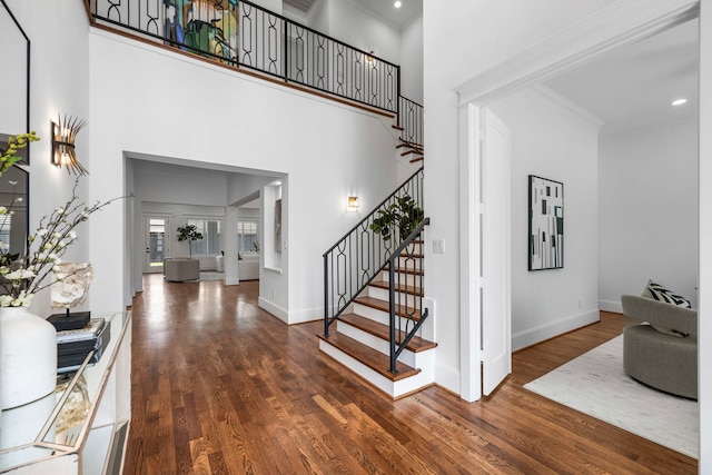 foyer featuring ornamental molding, dark hardwood / wood-style floors, and a high ceiling