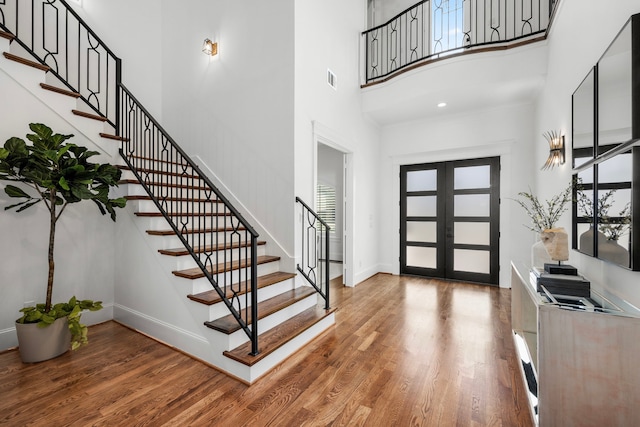 foyer with stairs, french doors, wood finished floors, and baseboards