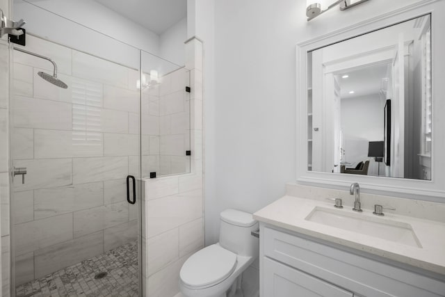 bathroom featuring vanity, toilet, and a shower with door