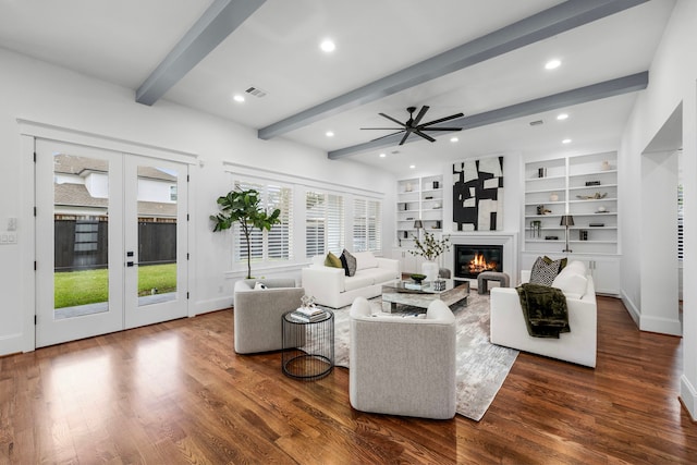 living area featuring wood finished floors, baseboards, french doors, beamed ceiling, and a glass covered fireplace