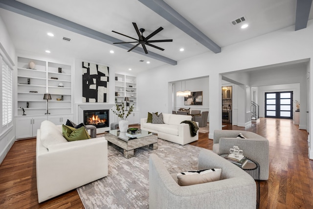 living room with built in features, wood-type flooring, beamed ceiling, and ceiling fan