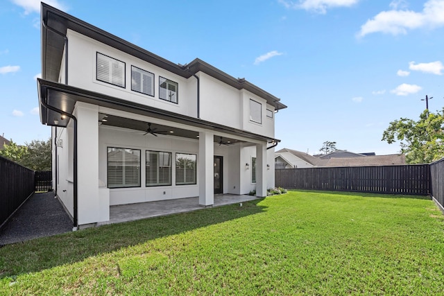 rear view of property with a lawn, ceiling fan, and a patio