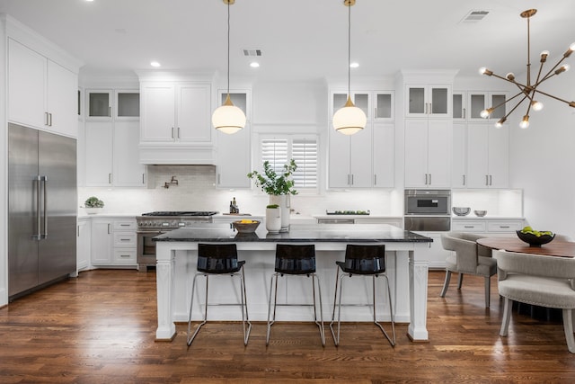 kitchen featuring high end appliances, white cabinetry, dark wood-type flooring, and a center island