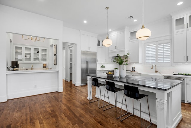 kitchen with white cabinets, a kitchen bar, and stainless steel built in refrigerator