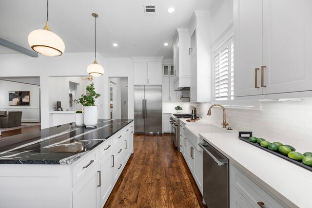 kitchen with white cabinetry, dark hardwood / wood-style floors, high end appliances, backsplash, and pendant lighting