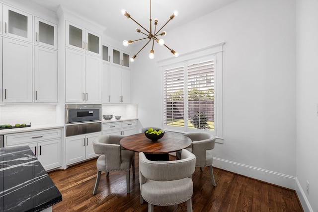 dining area with dark wood-type flooring and an inviting chandelier