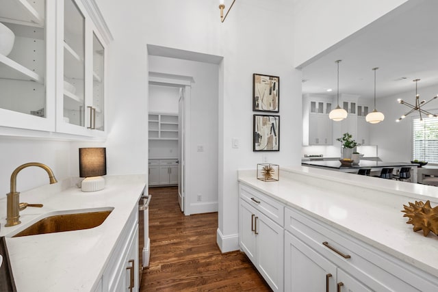 kitchen with white cabinets, dark hardwood / wood-style flooring, sink, and light stone countertops