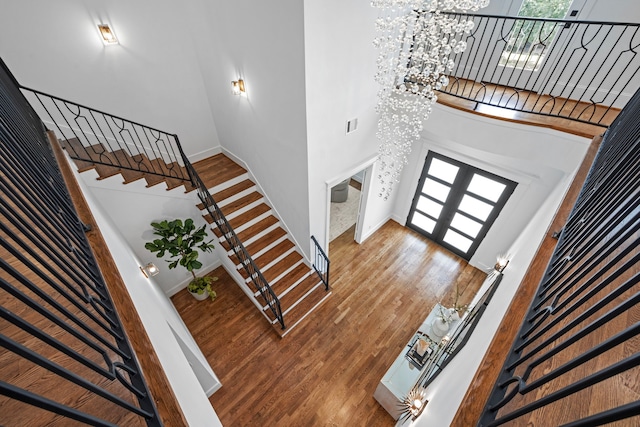 foyer with french doors, stairway, an inviting chandelier, wood finished floors, and plenty of natural light