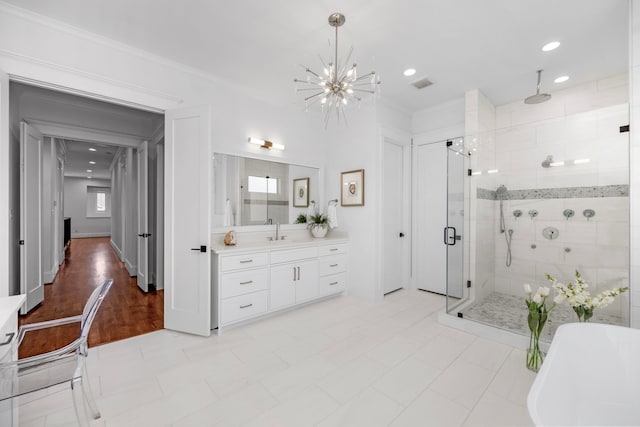 bathroom featuring a chandelier, a freestanding tub, vanity, ornamental molding, and a stall shower