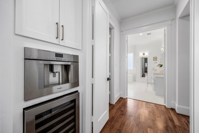 hall featuring baseboards, wine cooler, ornamental molding, and dark wood finished floors