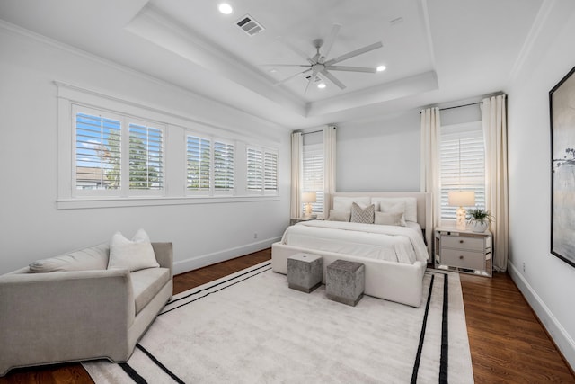 bedroom with crown molding, wood-type flooring, ceiling fan, and a raised ceiling