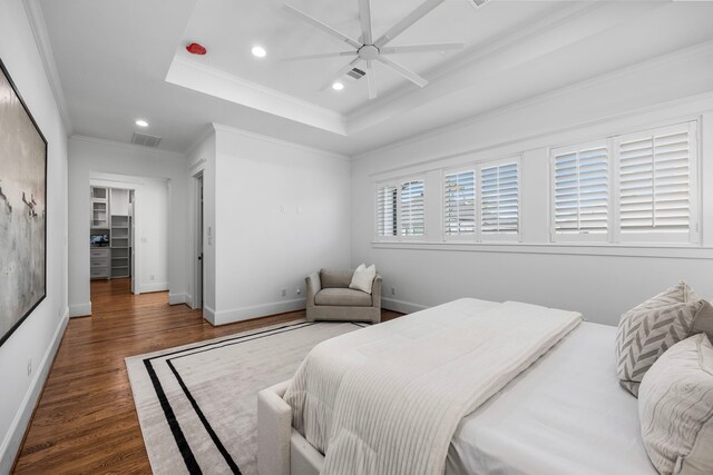 bedroom featuring ornamental molding, dark hardwood / wood-style flooring, ceiling fan, and a tray ceiling