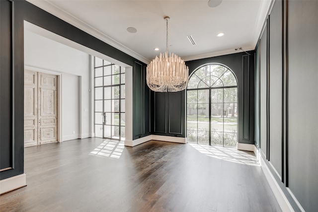 unfurnished dining area featuring a chandelier, hardwood / wood-style floors, and ornamental molding