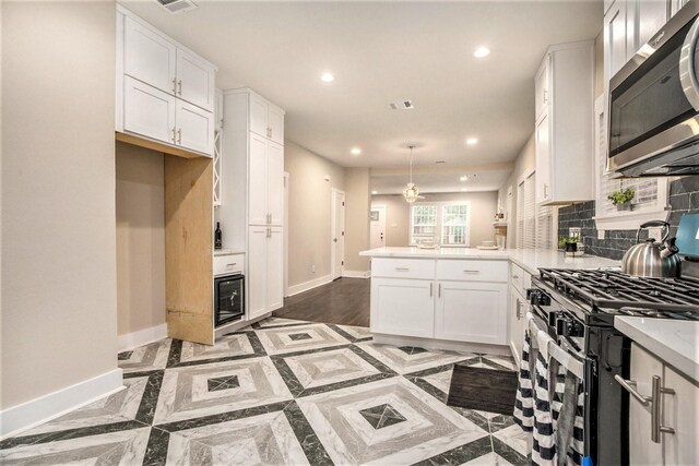 kitchen featuring kitchen peninsula, backsplash, stainless steel appliances, and white cabinetry