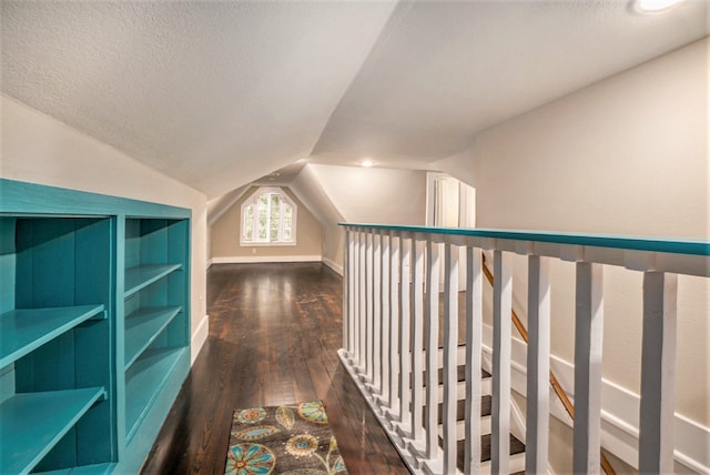 corridor with dark hardwood / wood-style flooring, a textured ceiling, and vaulted ceiling