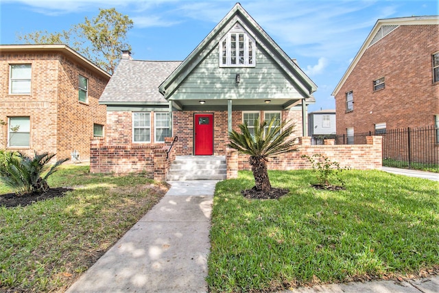 view of front facade featuring brick siding, fence, roof with shingles, a front lawn, and a chimney