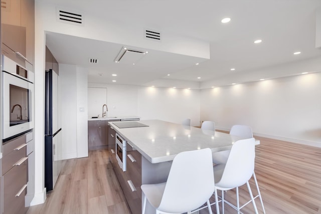 kitchen featuring a center island, sink, oven, light hardwood / wood-style flooring, and fridge