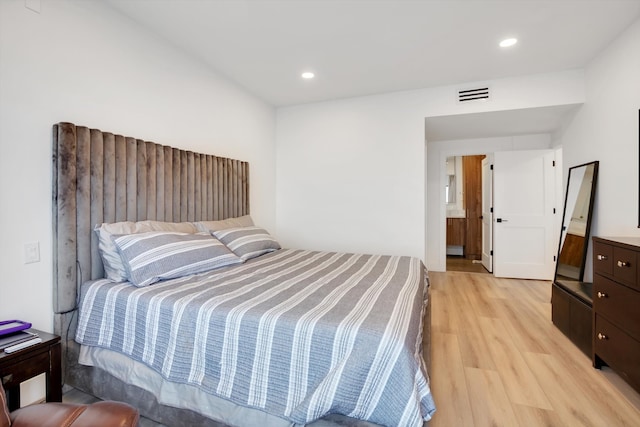 bedroom with connected bathroom and light hardwood / wood-style flooring