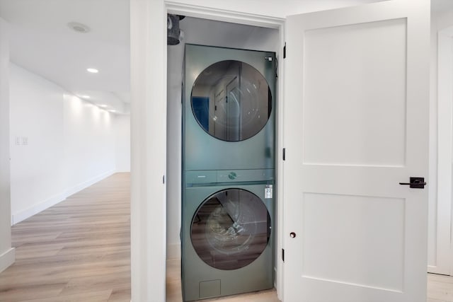 clothes washing area with light hardwood / wood-style floors and stacked washer / dryer