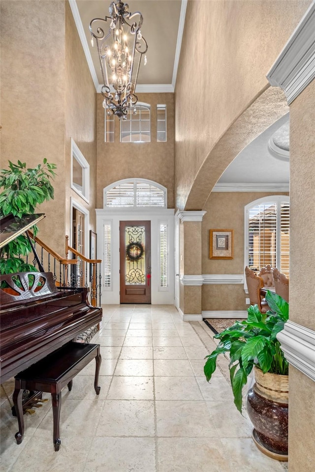 entrance foyer with a high ceiling, an inviting chandelier, crown molding, and ornate columns