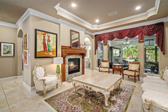 living area with a tiled fireplace and crown molding