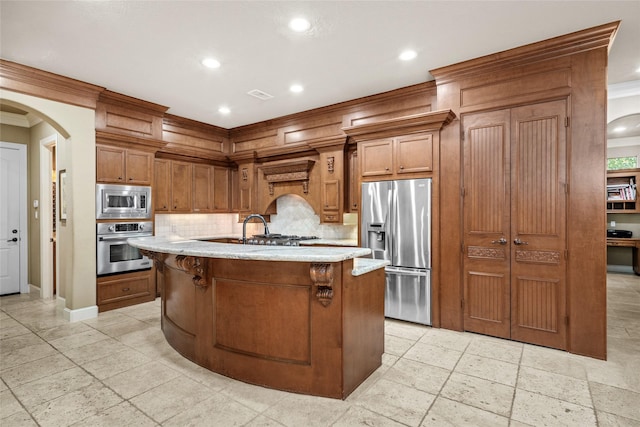 kitchen featuring backsplash, ornamental molding, a breakfast bar, stainless steel appliances, and a center island with sink