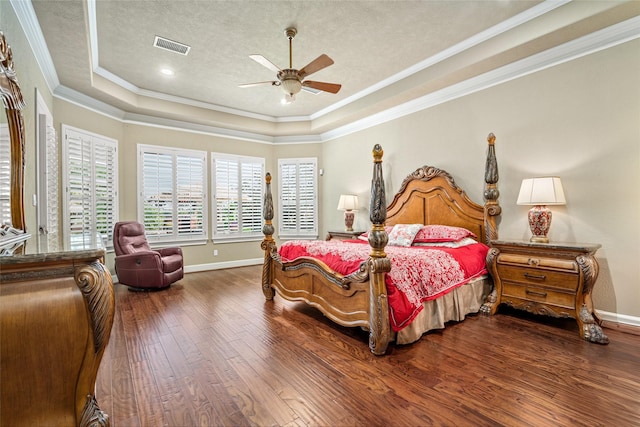 bedroom with dark hardwood / wood-style flooring, a tray ceiling, ceiling fan, and crown molding