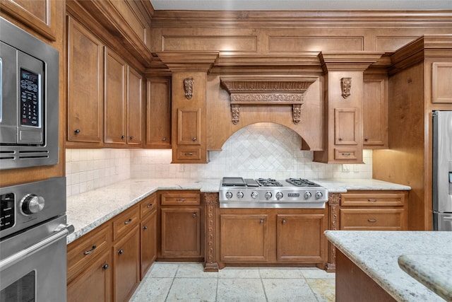 kitchen with decorative backsplash, light stone counters, custom range hood, and appliances with stainless steel finishes