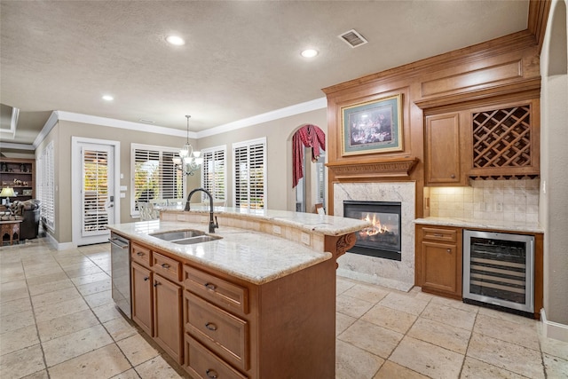 kitchen with sink, pendant lighting, a premium fireplace, wine cooler, and an island with sink