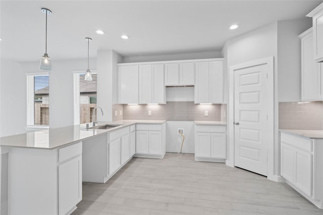 373 Spruce Oak Ln, Waller, TX 77484 - kitchen featuring a sink, backsplash, light wood-type flooring, recessed lighting, and hanging light fixtures